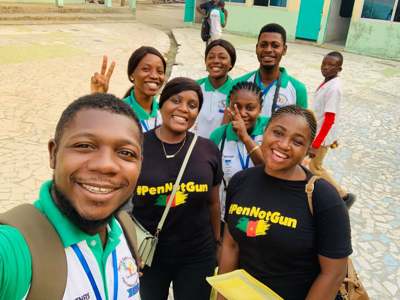 Joyful group of people taking a selfie with matching outfits with the word "#PenNotGun" written on them